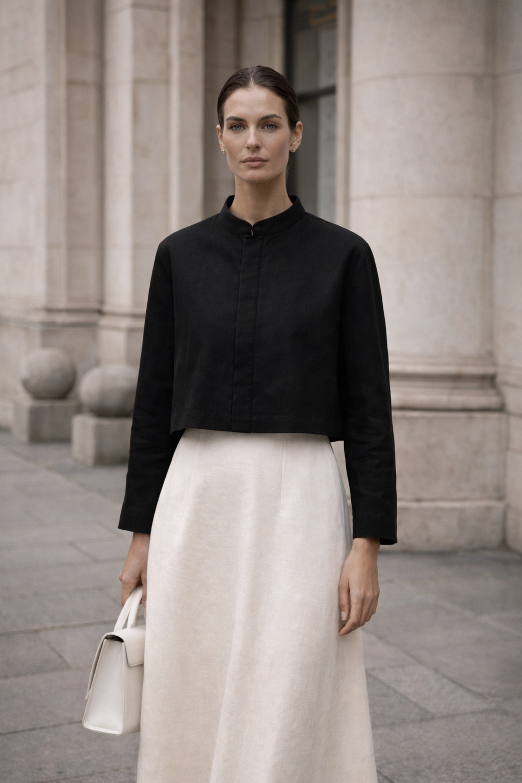 Woman wearing a black shirt and white pants standing in front of stone halden shirt columns.